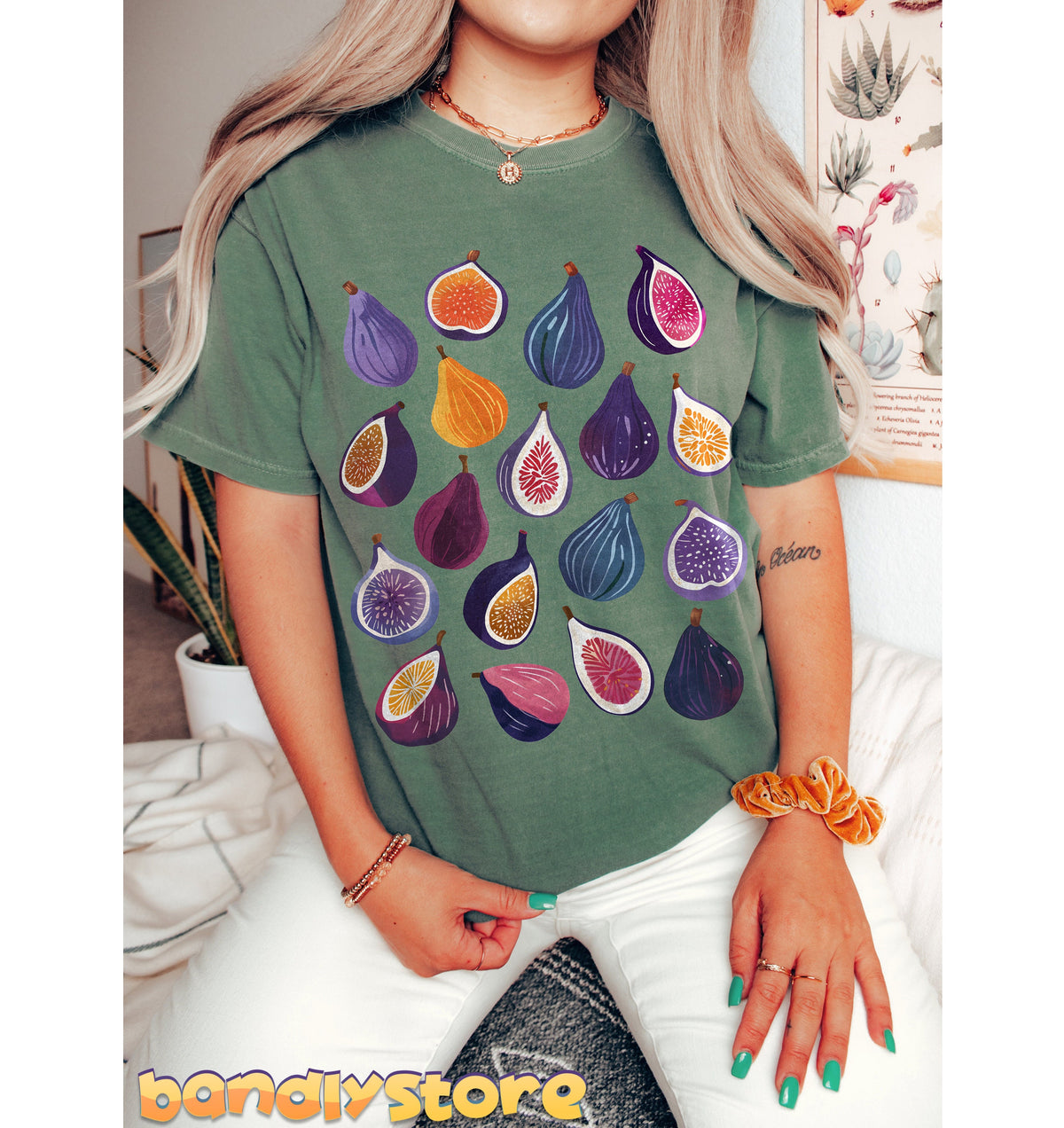 Boho Fig T-Shirt in Blue Spruce on a seated person facing forward amid indoor plants and wall art in Moss