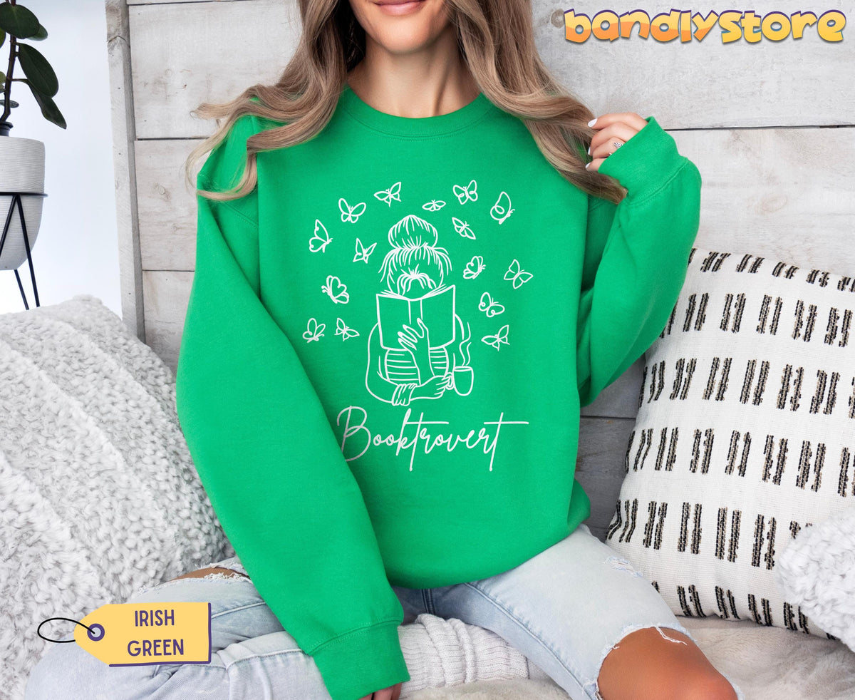 Booktrovert Sweatshirt in Irish Green on seated model in front of wood wall with pillows and plant.