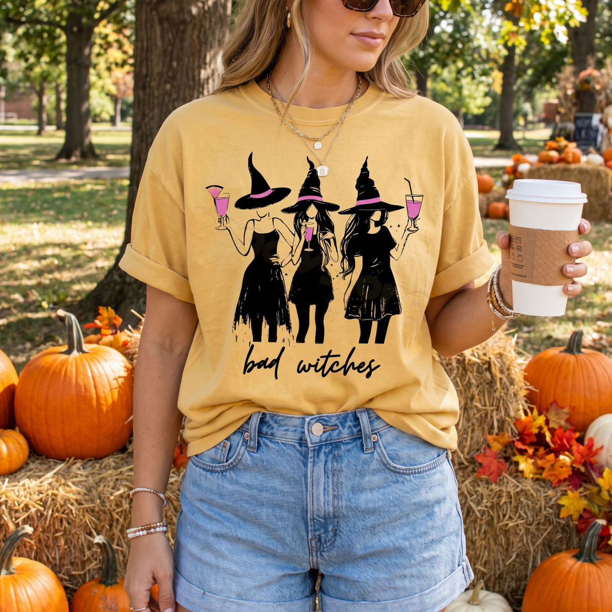 Boujee Bad Witches T-Shirt in mustard, front view outdoors amid pumpkins, hay bales and a coffee cup.