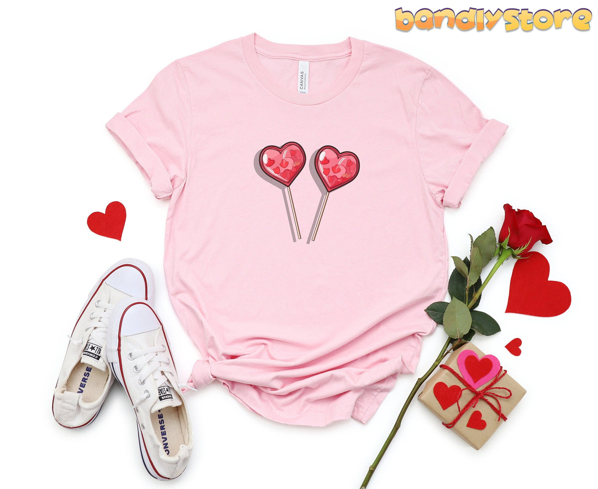 Cute Candy Hearts T-Shirt in pink flat lay with heart lollipops beside sneakers, rose and gift.
