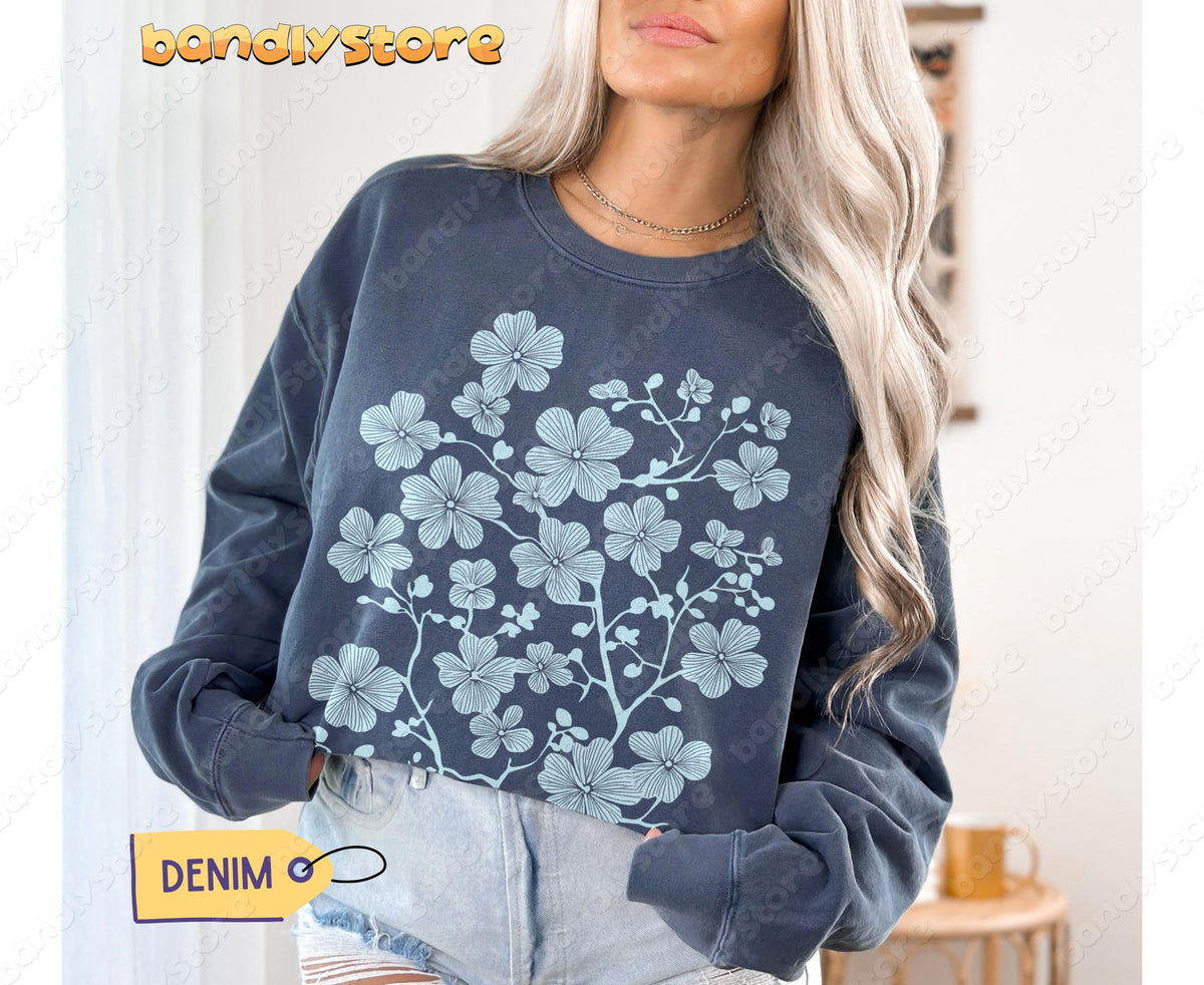 Cherry Blossom Linocut Sweatshirt in denim, front view on a model indoors with light curtains and a side table.