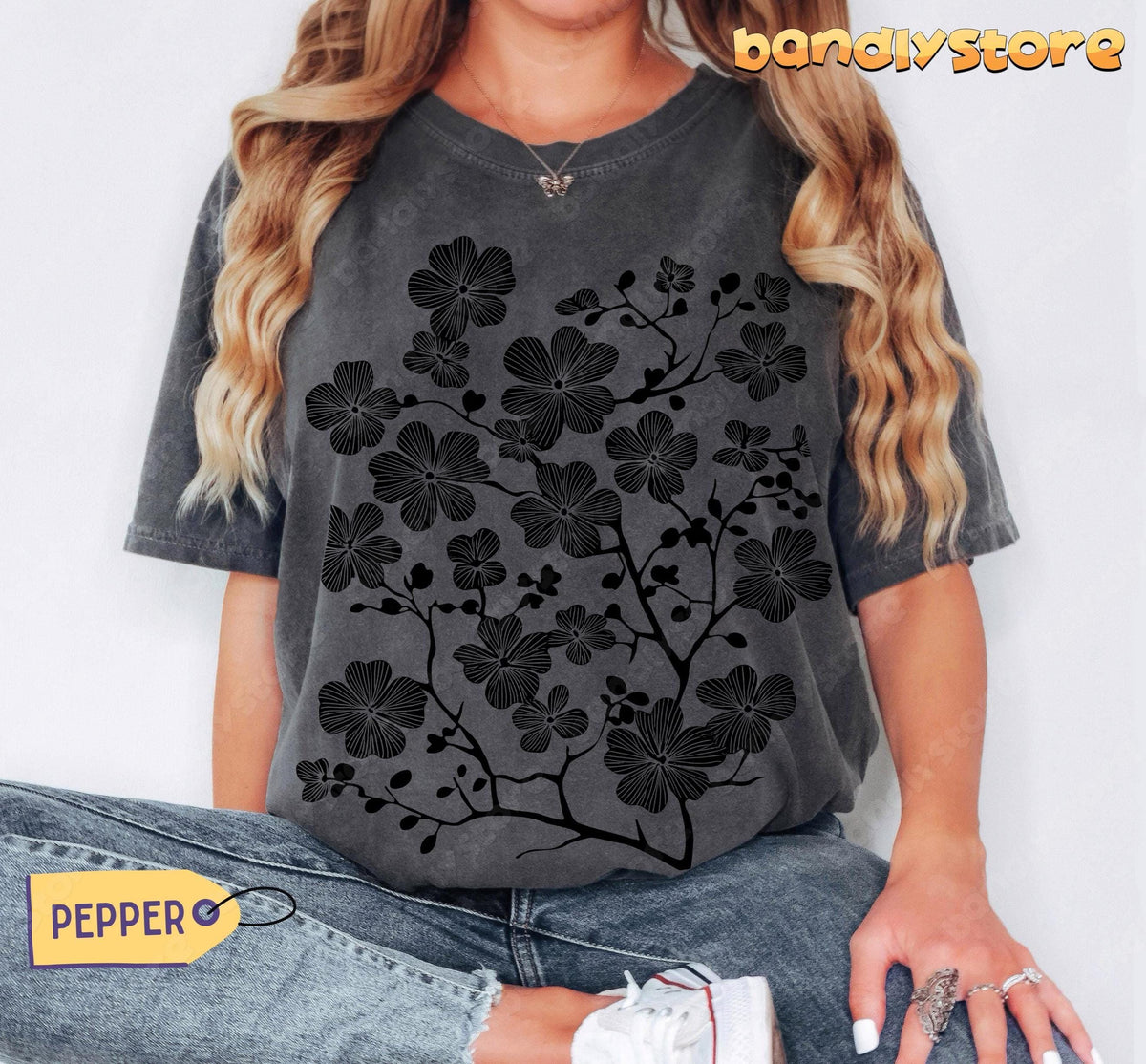 Cherry Blossom Linocut T-Shirt in Pepper in front view on seated woman in jeans and sneakers on plain background.