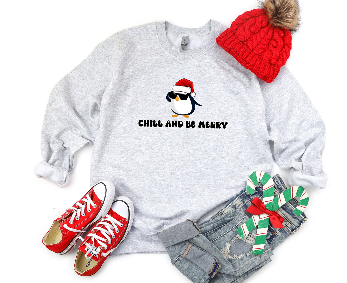 Chill And Be Merry Penguin Sweatshirt in ash, flat-laid with red beanie, sneakers, jeans and candy canes.