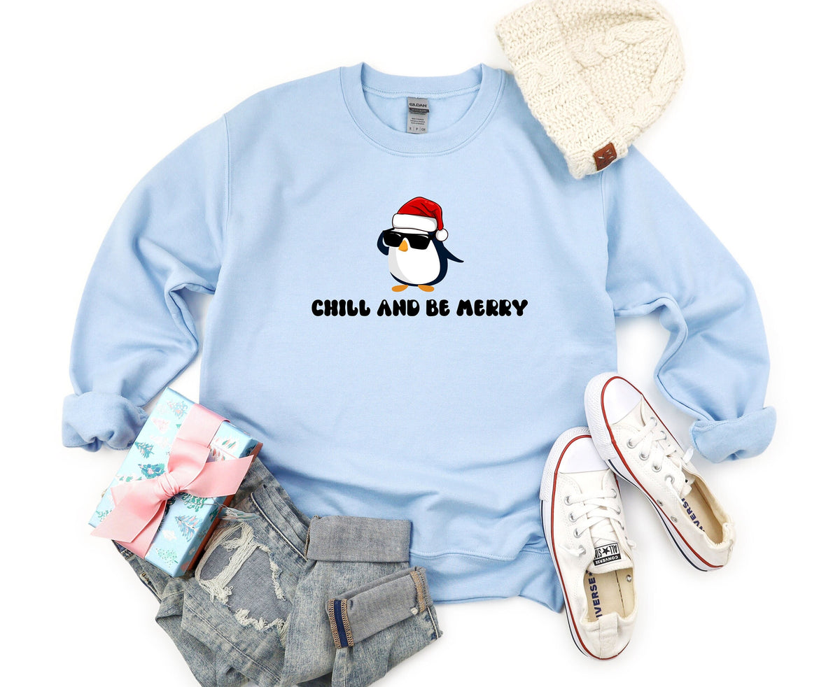 Chill And Be Merry Penguin Sweatshirt in light blue laid flat from above with beanie, gift, jeans and sneakers.