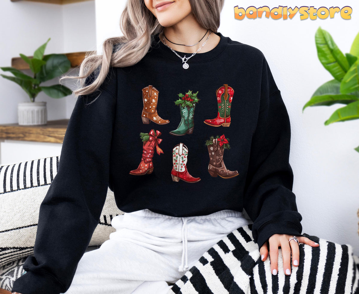 Christmas Cowgirl Boots Sweatshirt in black on a seated model amid indoor plants and striped pillows.