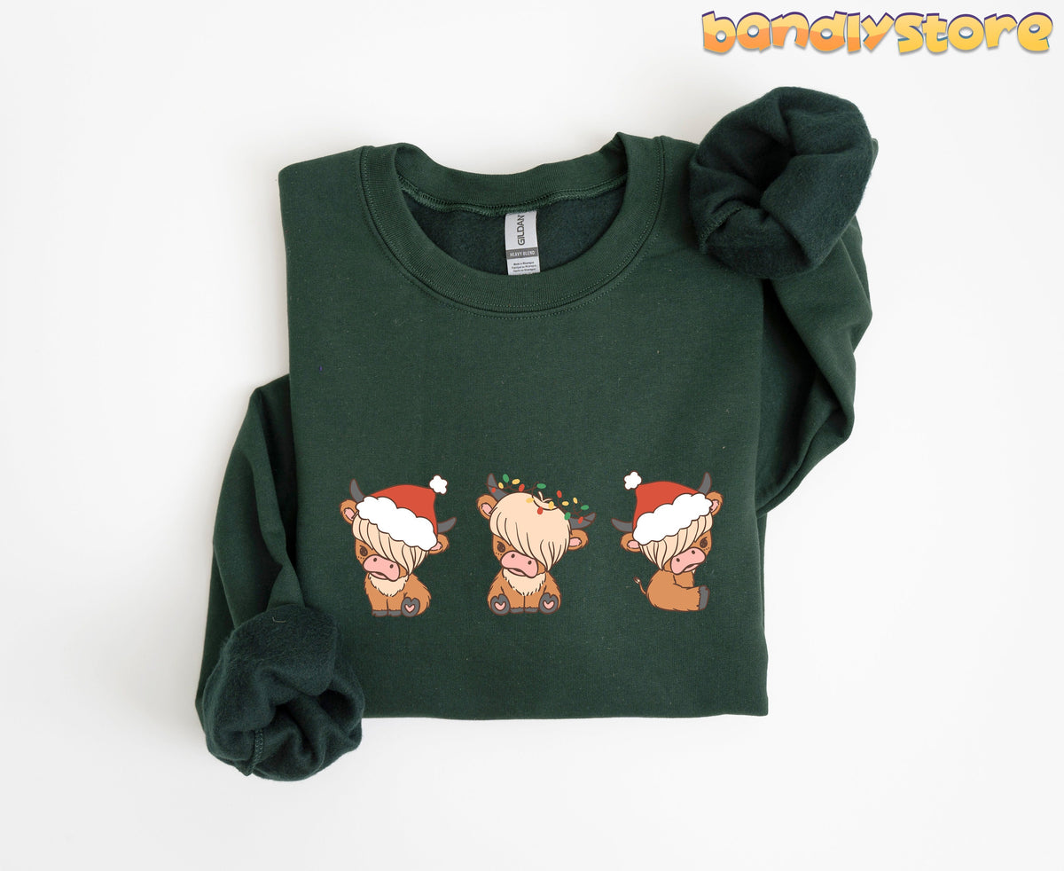 Christmas Highland Cow Trio Sweatshirt in forest green folded flat on a white background.