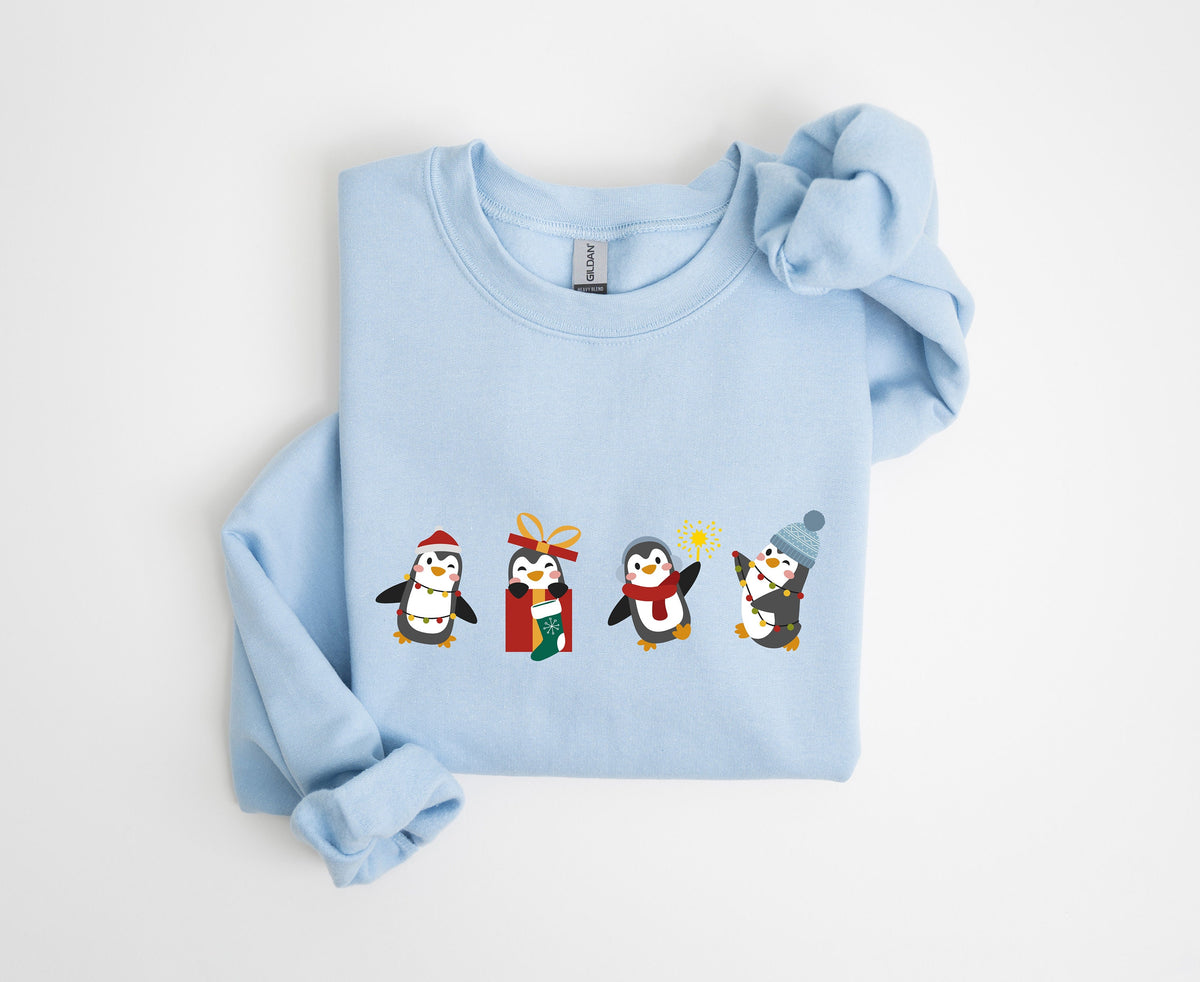 Christmas Penguin Sweatshirt light blue folded flat on plain white background in top-down view.