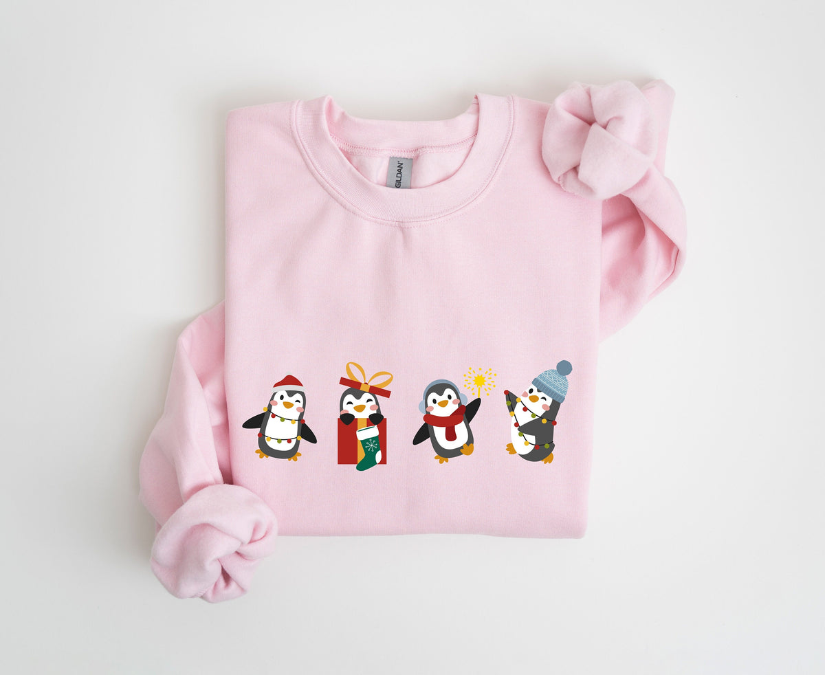 Christmas Penguin Sweatshirt in light pink folded flat on a plain white background, top-down view.