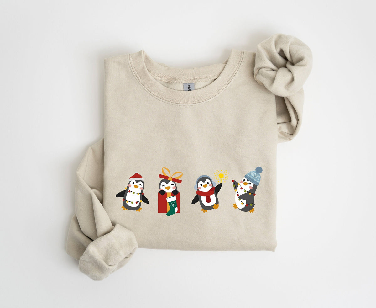 Christmas Penguin Sweatshirt in sand folded flat on a plain white background viewed from above.