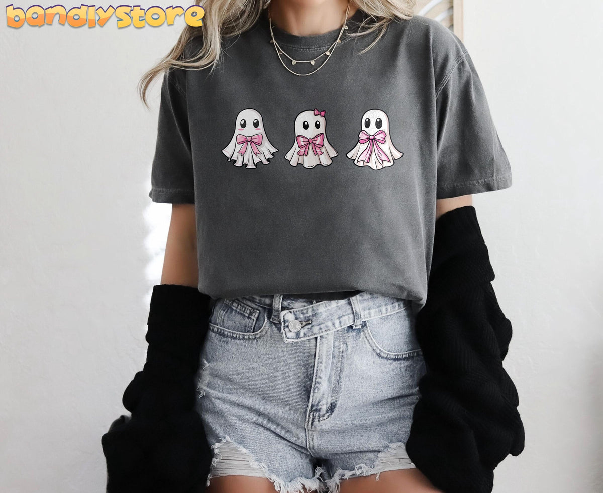 Cute Coquette Ghost T-Shirt in Pepper on a front-facing person against a plain wall with black sleeves and denim shorts.
