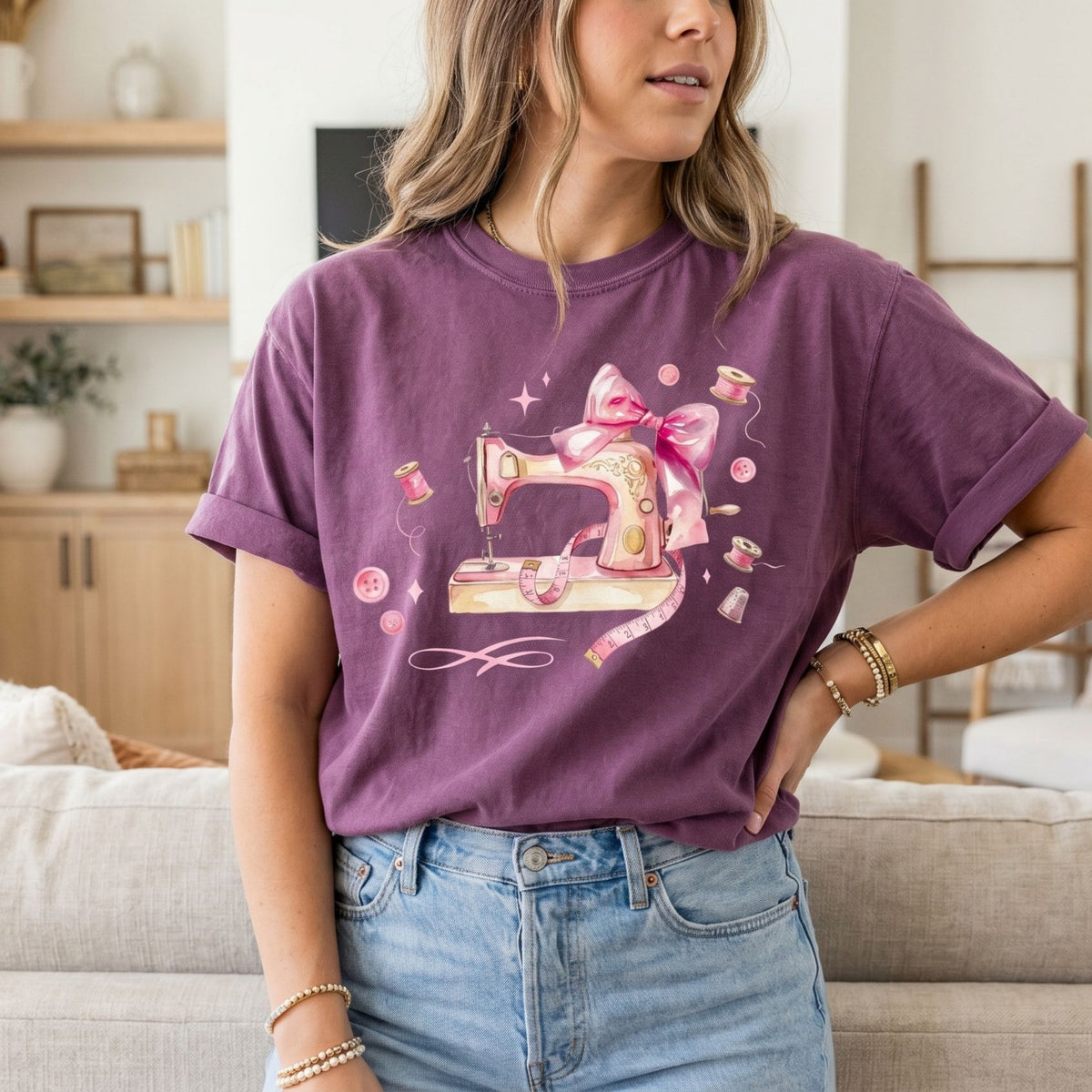 Coquette Sewing T-Shirt in berry on a woman in a living room, front view with sofa and shelves behind.