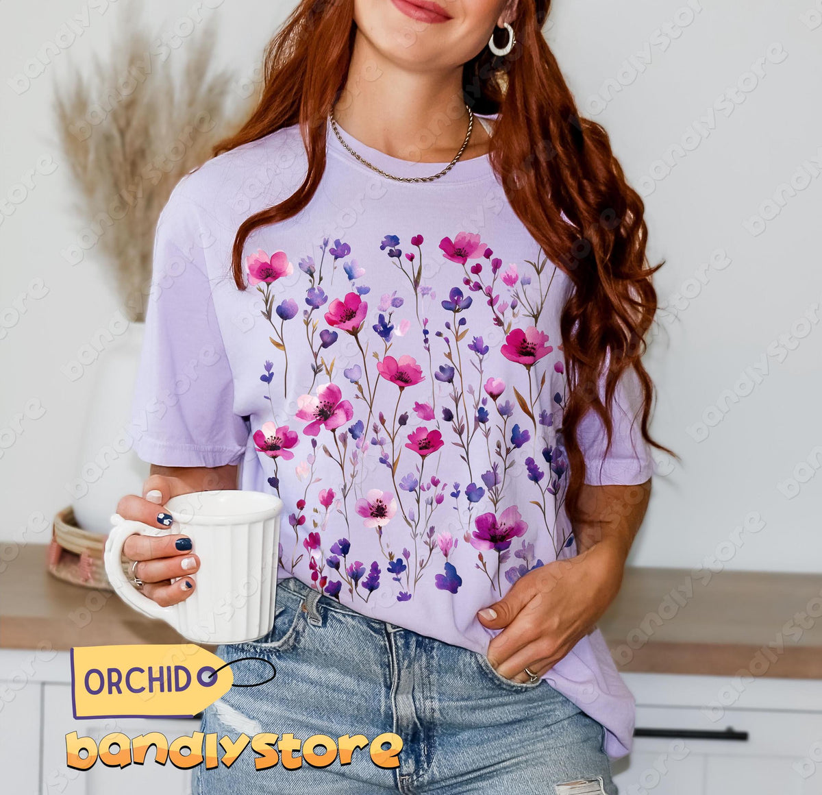Pressed Wildflowers T-Shirt in orchid worn by a woman holding a white mug in a kitchen, front view.