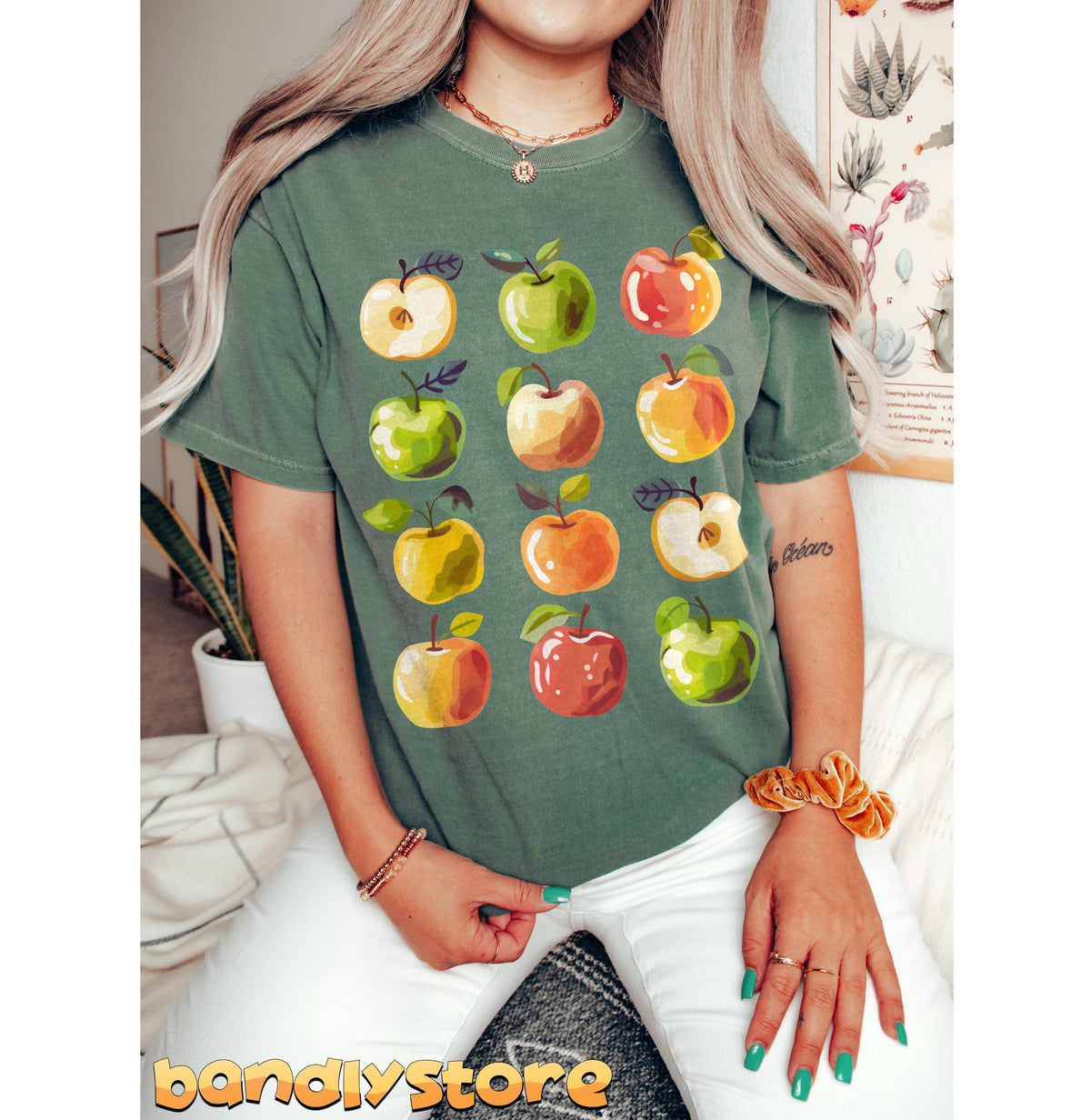 Cute Apples T-Shirt on a person seated frontally indoors beside plants and a wall poster, green in Light Green