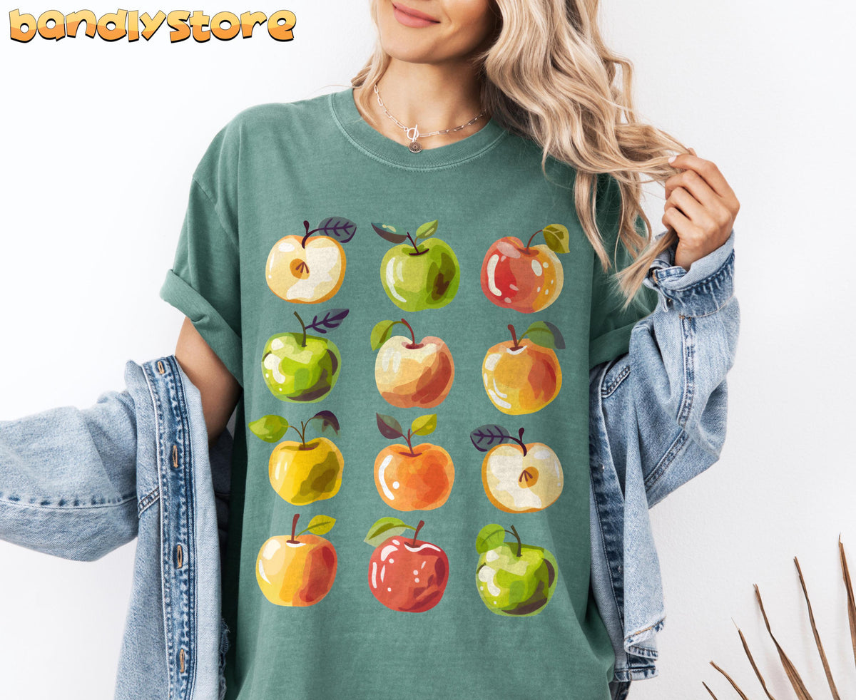 Cute Apples T-Shirt shown front-on on a person with open denim jacket against a white wall in Moss