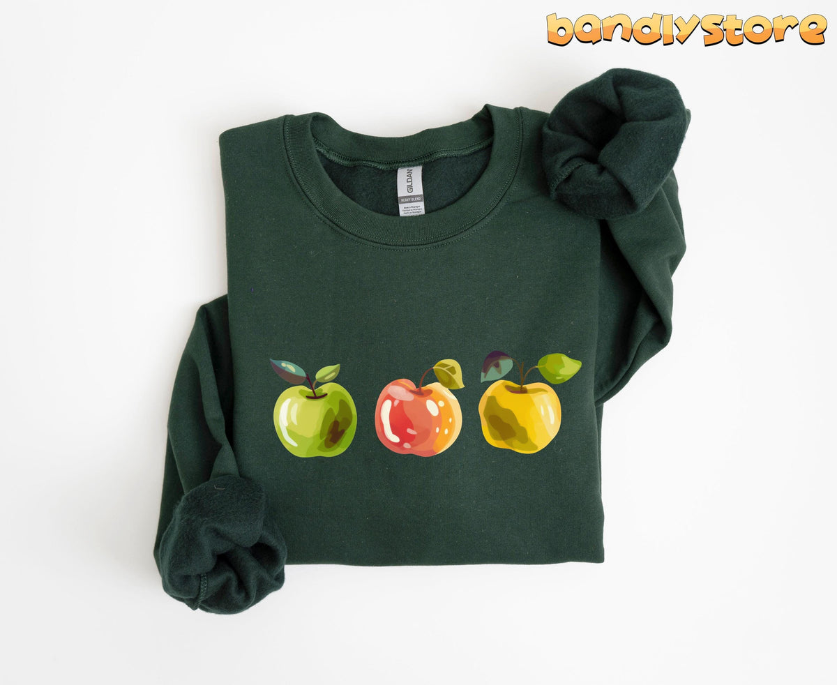 Cute Apples Sweatshirt in forest green, folded flat on white with three illustrated apples across the chest.