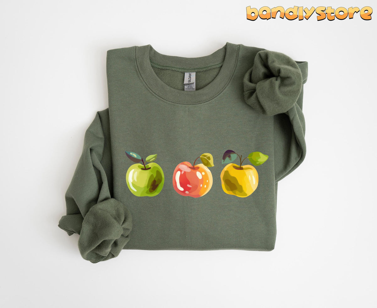 Cute Apples Sweatshirt in military green, folded flat on white with three illustrated apples across the chest.