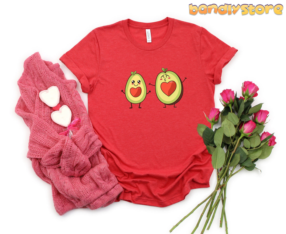 Cute Avocado Love T-Shirt in red flat-laid from above beside pink knit with hearts and roses.