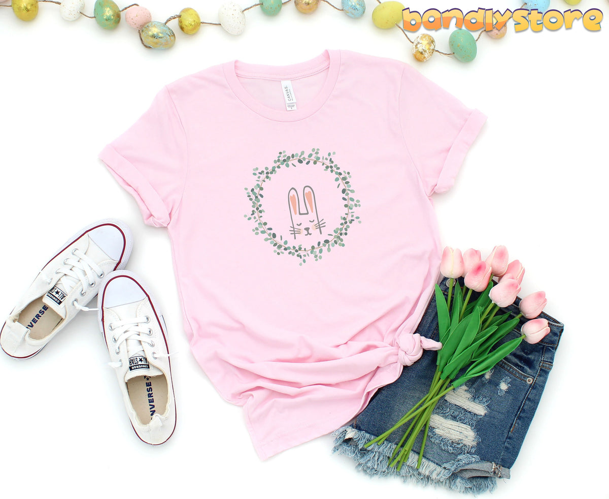Cute Bunny T-Shirt in pink laid flat beside white sneakers, denim shorts, tulips and egg garland.