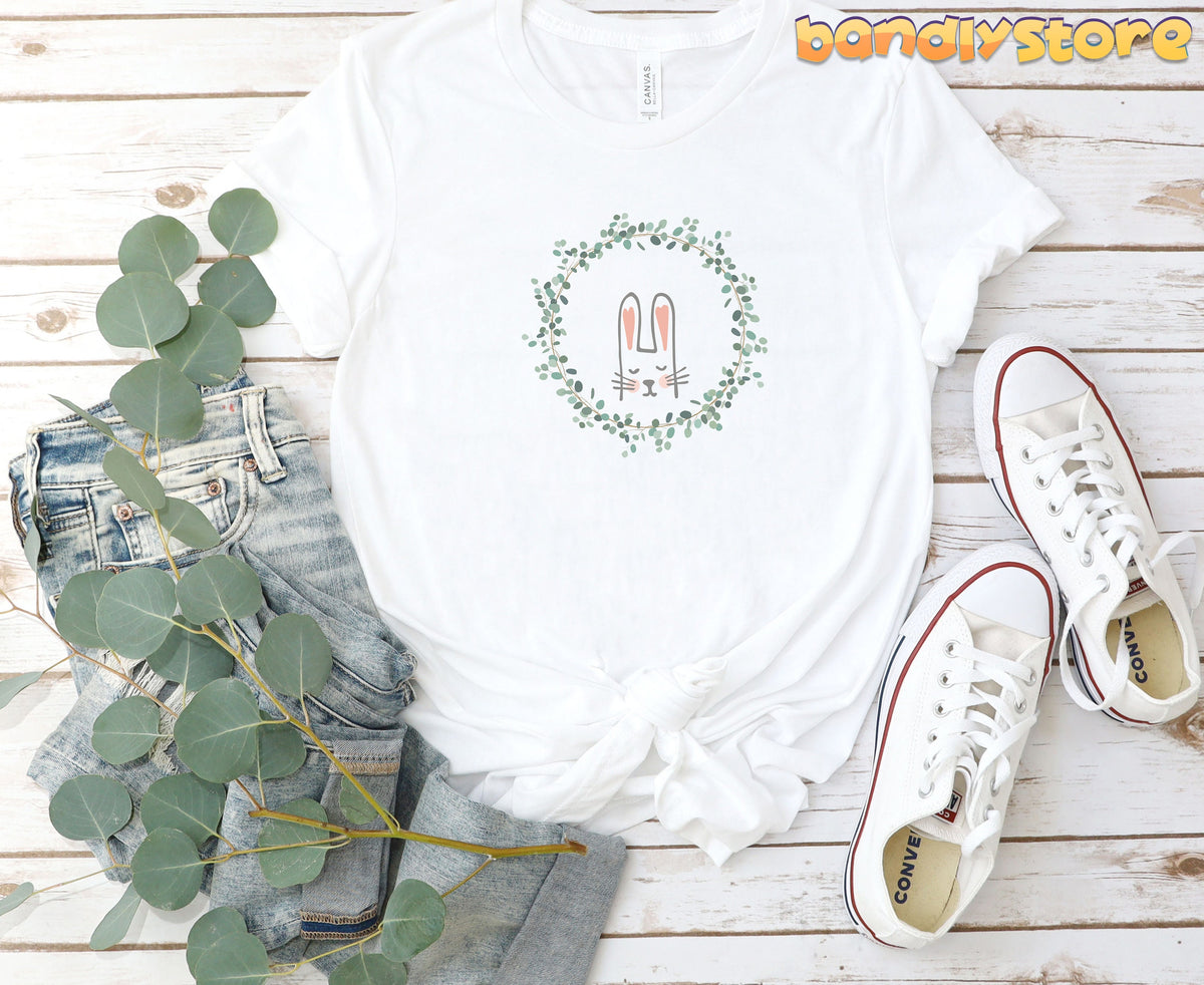 Cute Bunny T-Shirt in white laid flat on wooden boards with jeans, eucalyptus and sneakers.