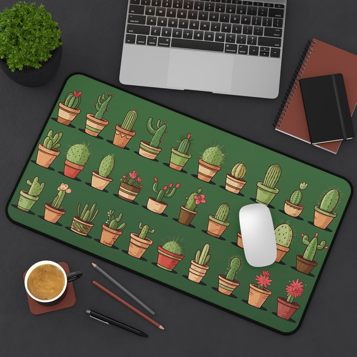 Cute Cacti Desk Mat top-down on a desk with laptop, plant, notebooks, coffee, pens and mouse, 12 × 22 inches.