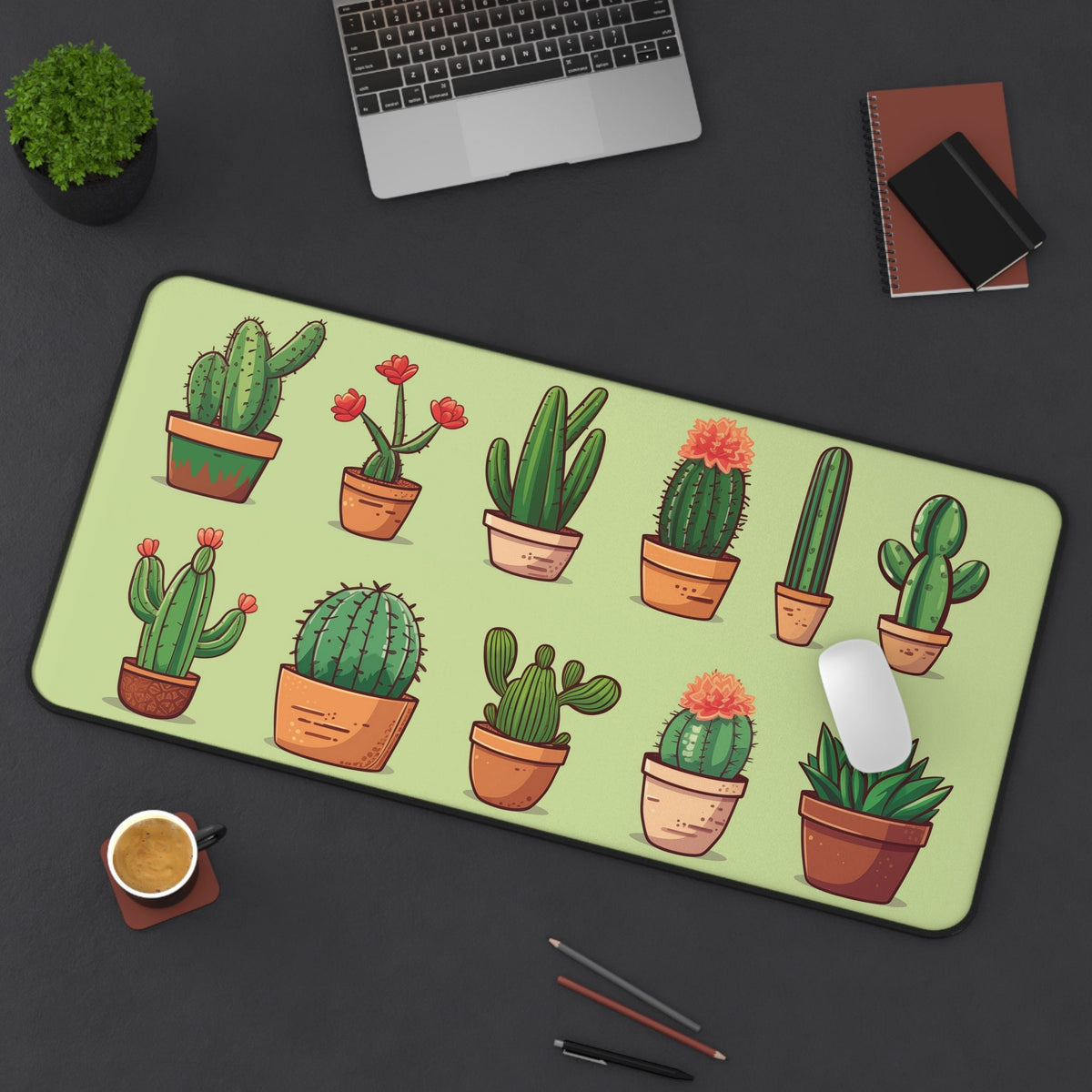 Cute Cactus Desk Mat 16 × 32 inches from above on dark desk next to laptop, plant, notebooks, coffee, pens and mouse.