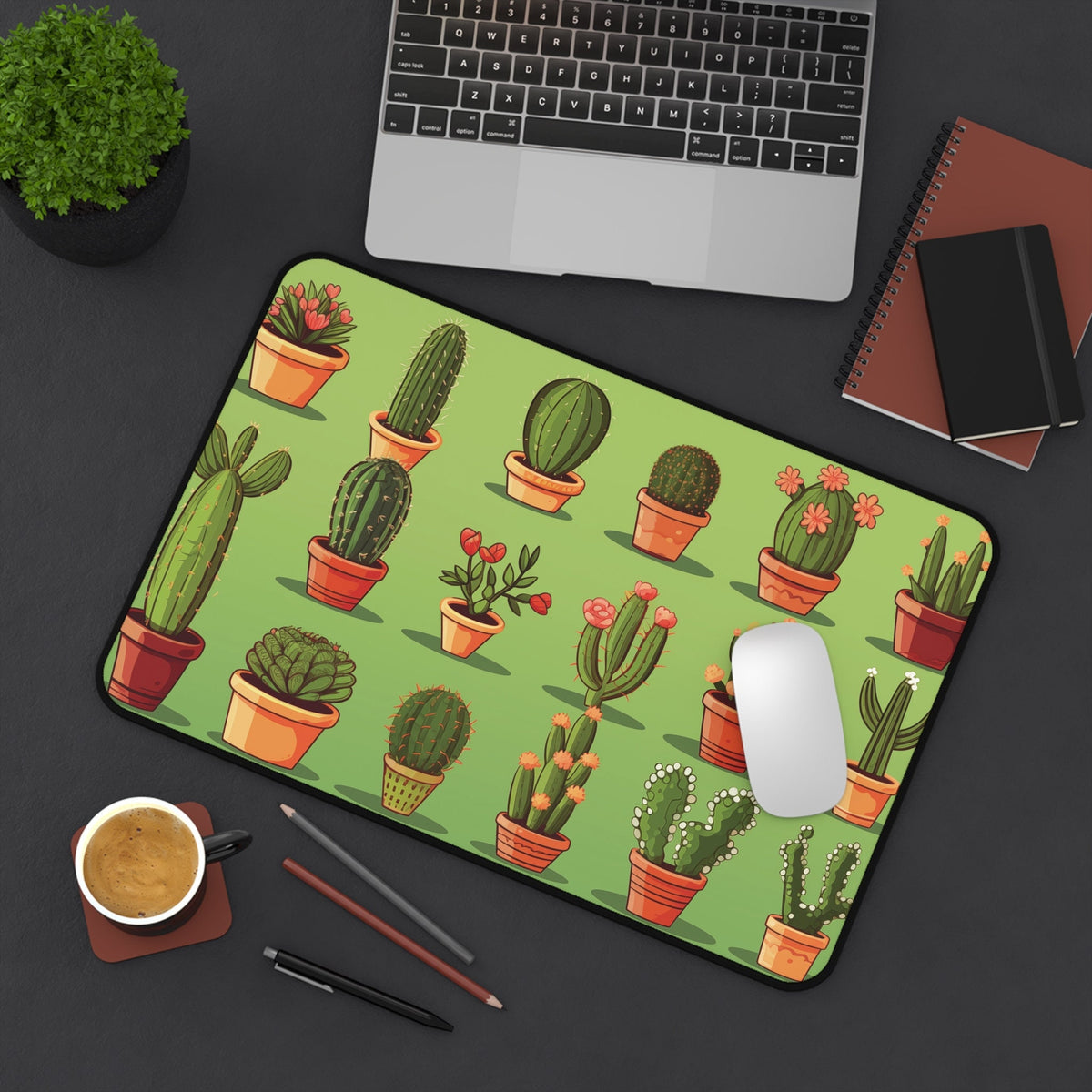 Cute Cactuses Desk Mat on a dark desk beside a laptop, mouse, coffee, and notebooks, green 12 × 18 inches pattern.
