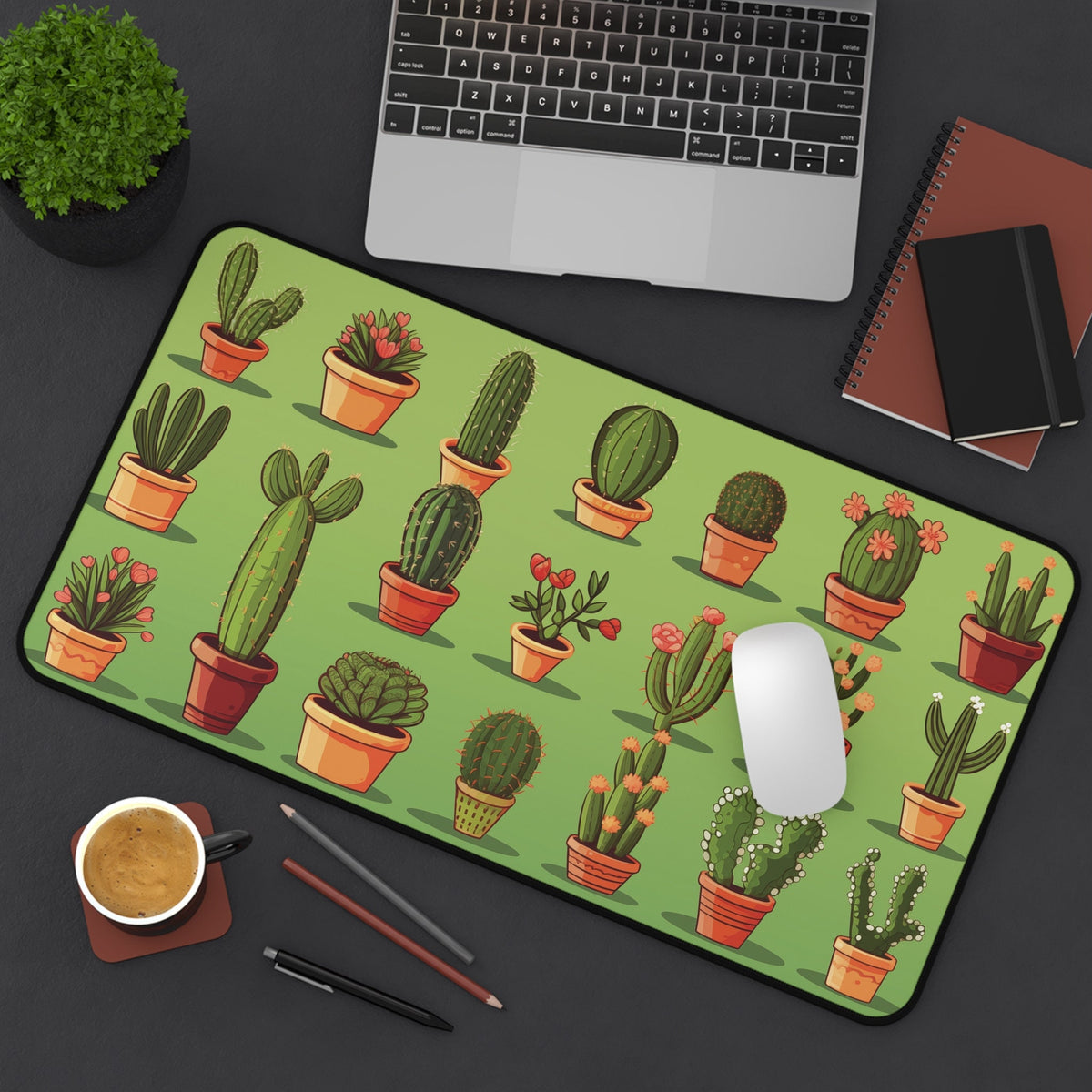 Cute Cactuses Desk Mat on a dark desk beside a laptop, mouse, coffee, pens and notebooks, green pattern, 12 × 22 inches.