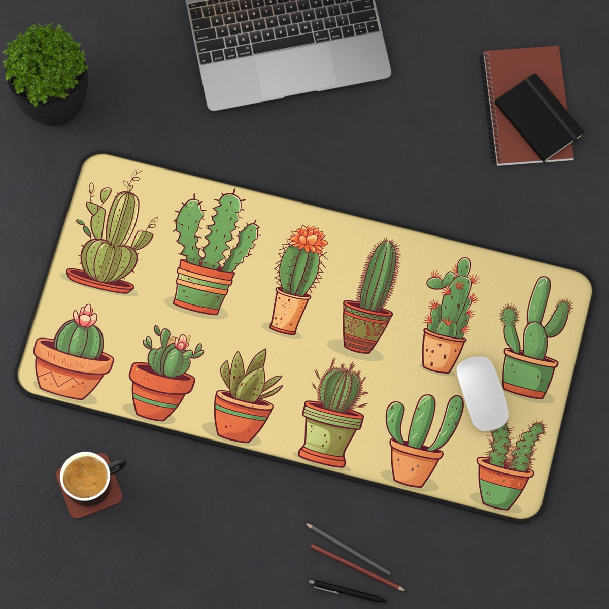 Cute Cactuses Desk Mat on a dark desk with laptop, plant, coffee, notebooks and pens, pale yellow 16 × 32 inches surface.