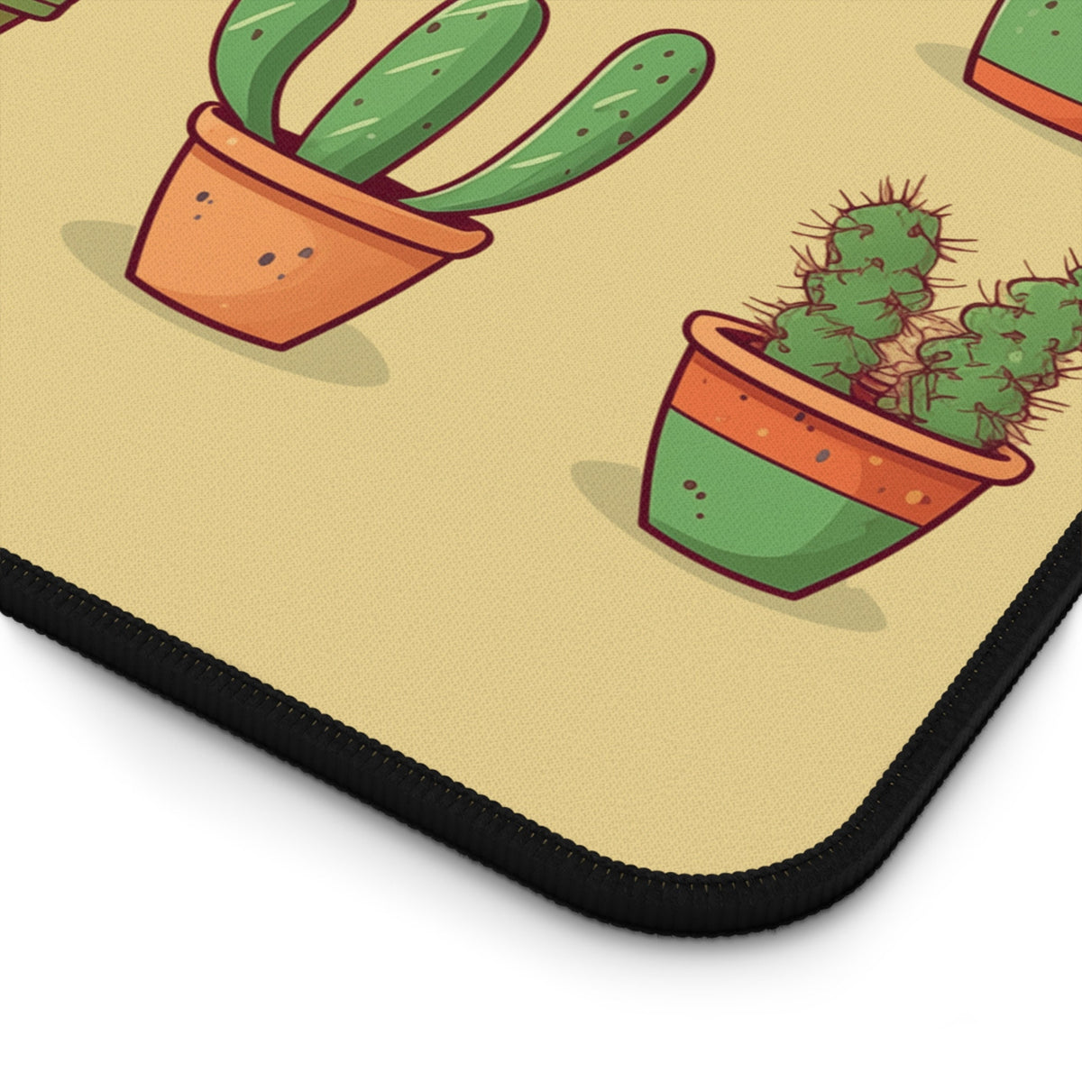 Cute Cactuses Desk Mat detail of the black-stitched corner showing cartoon potted cacti on a beige surface.
