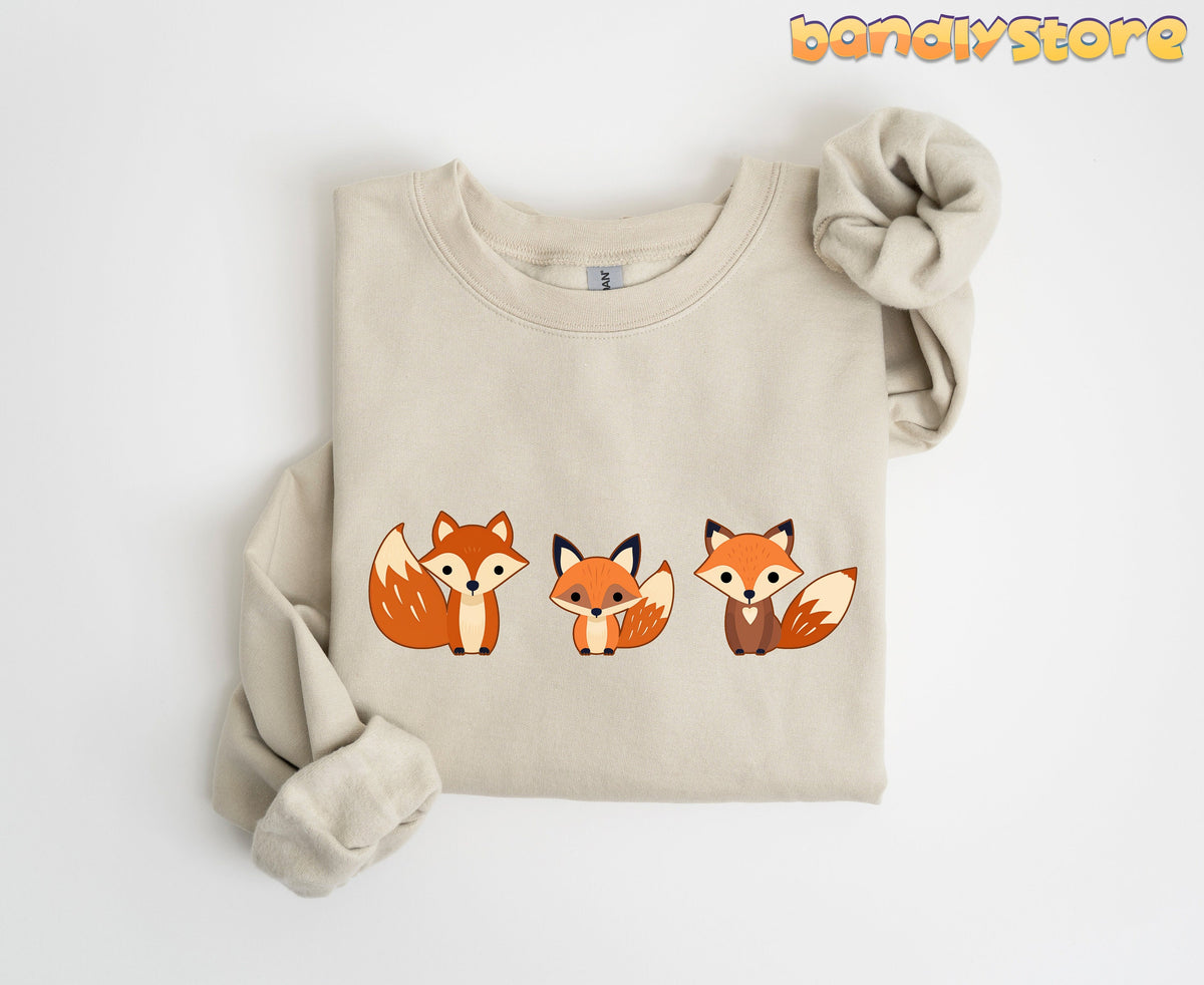 Cute Fox Sweatshirt in sand, folded flat on white with three cartoon foxes across the chest.