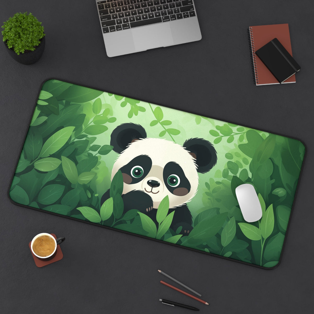 Cute Kawaii Panda Desk Mat in green jungle leaves on a dark desk with laptop, plant, coffee and mouse, 16 × 32 inches.