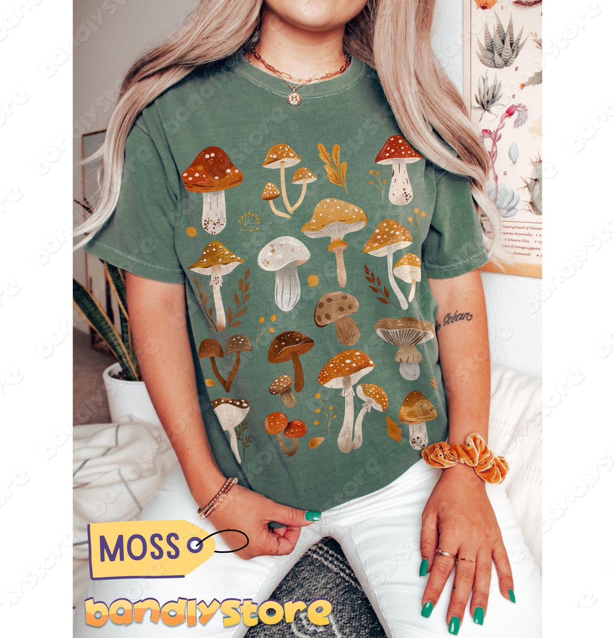 Cute Mushrooms T-Shirt in moss shown front-on on a seated person surrounded by houseplants and a wall poster.