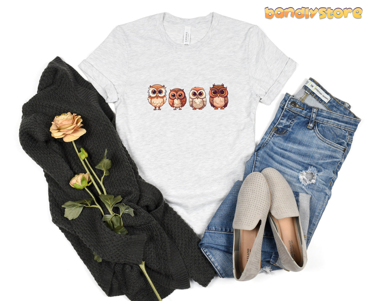 Cute Owl T-Shirt in Athletic Heather laid flat beside dark knit throw, roses, jeans and loafers.