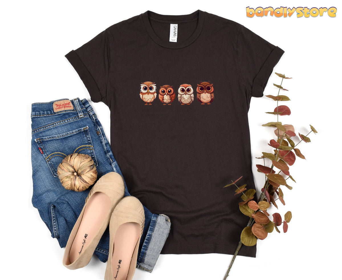 Cute Owl T-Shirt in brown, flat-laid with jeans, beige flats, a small pumpkin and autumn foliage.