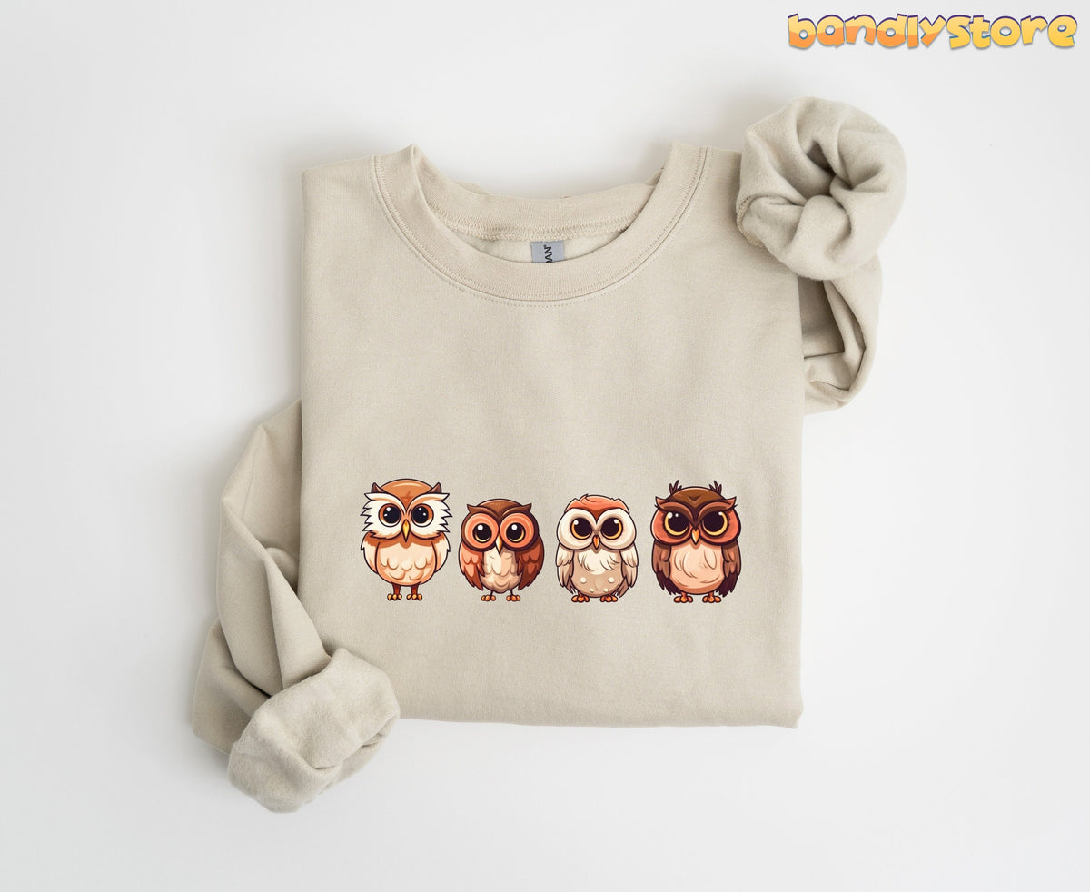 Cute Owl Sweatshirt in sand folded flat on white background with four cartoon owls across the chest.