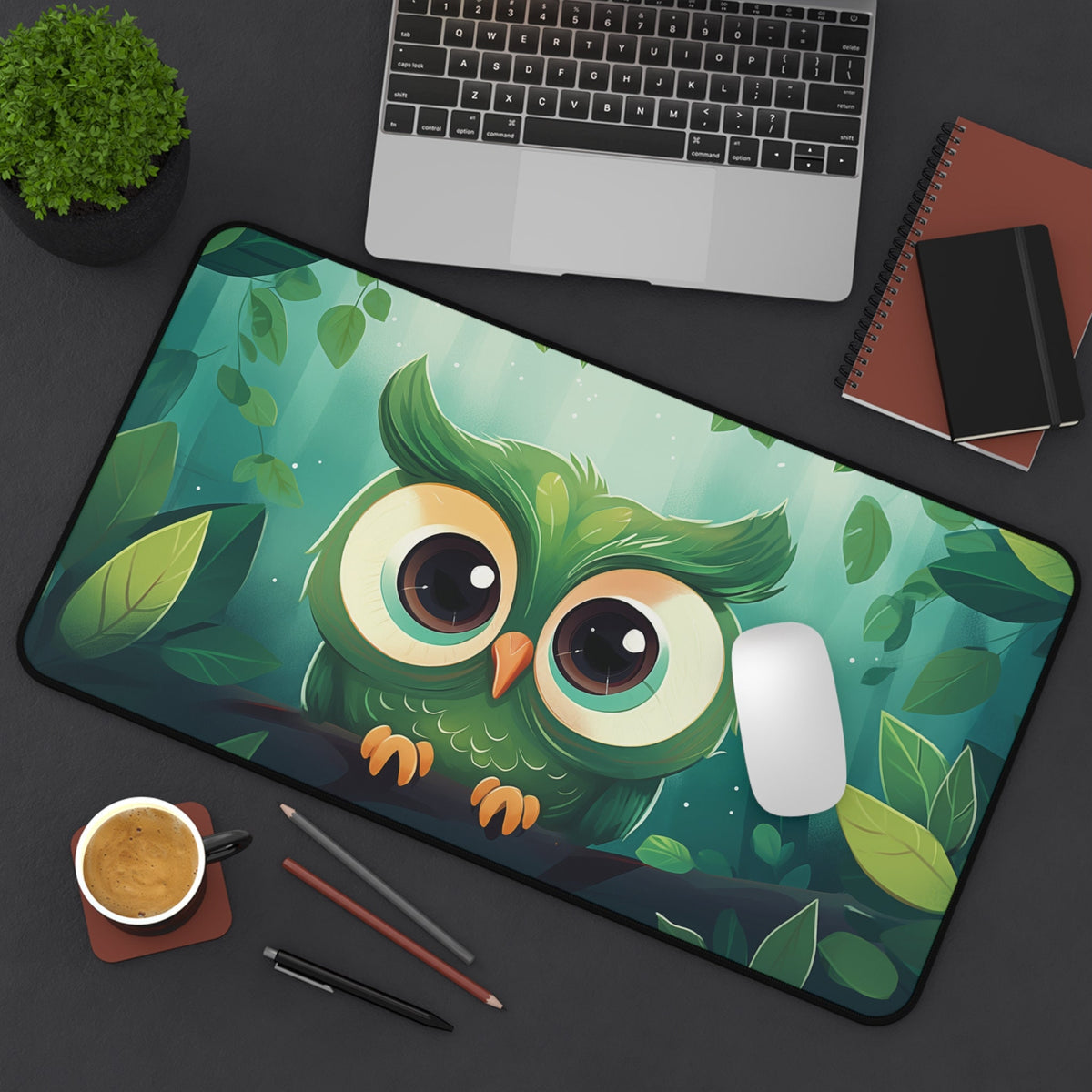 Cute Owl Desk Mat 12 × 22 inches from above on a dark desk with laptop, plant, coffee, pencils, notebooks and mouse.