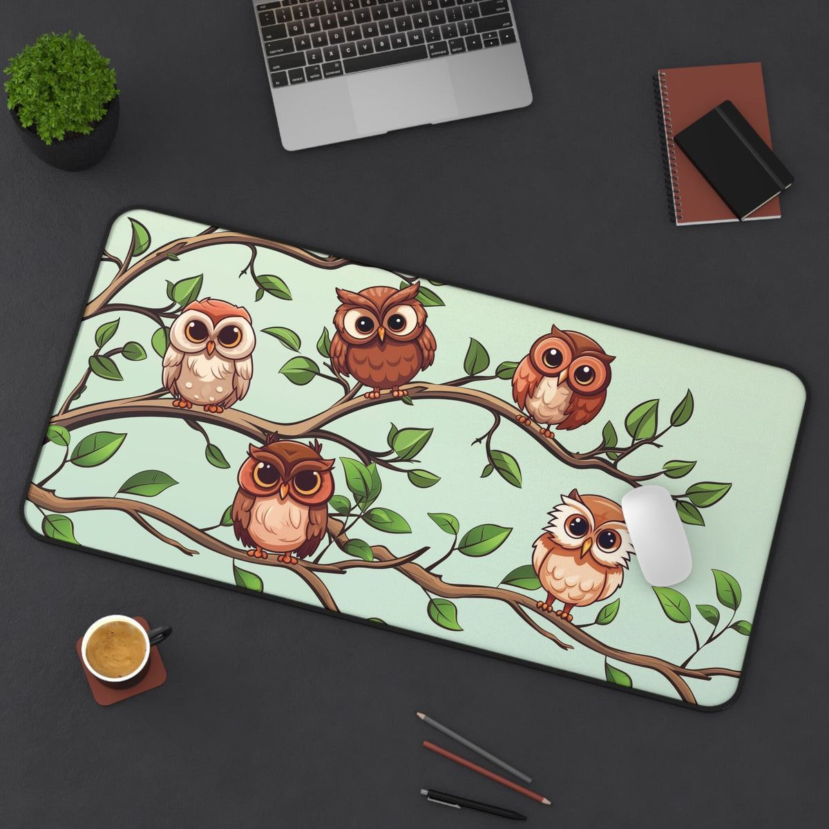 Cute Owls Desk Mat 16 × 32 inches on dark desk with laptop, plant, coffee cup, mouse and pencils from above.