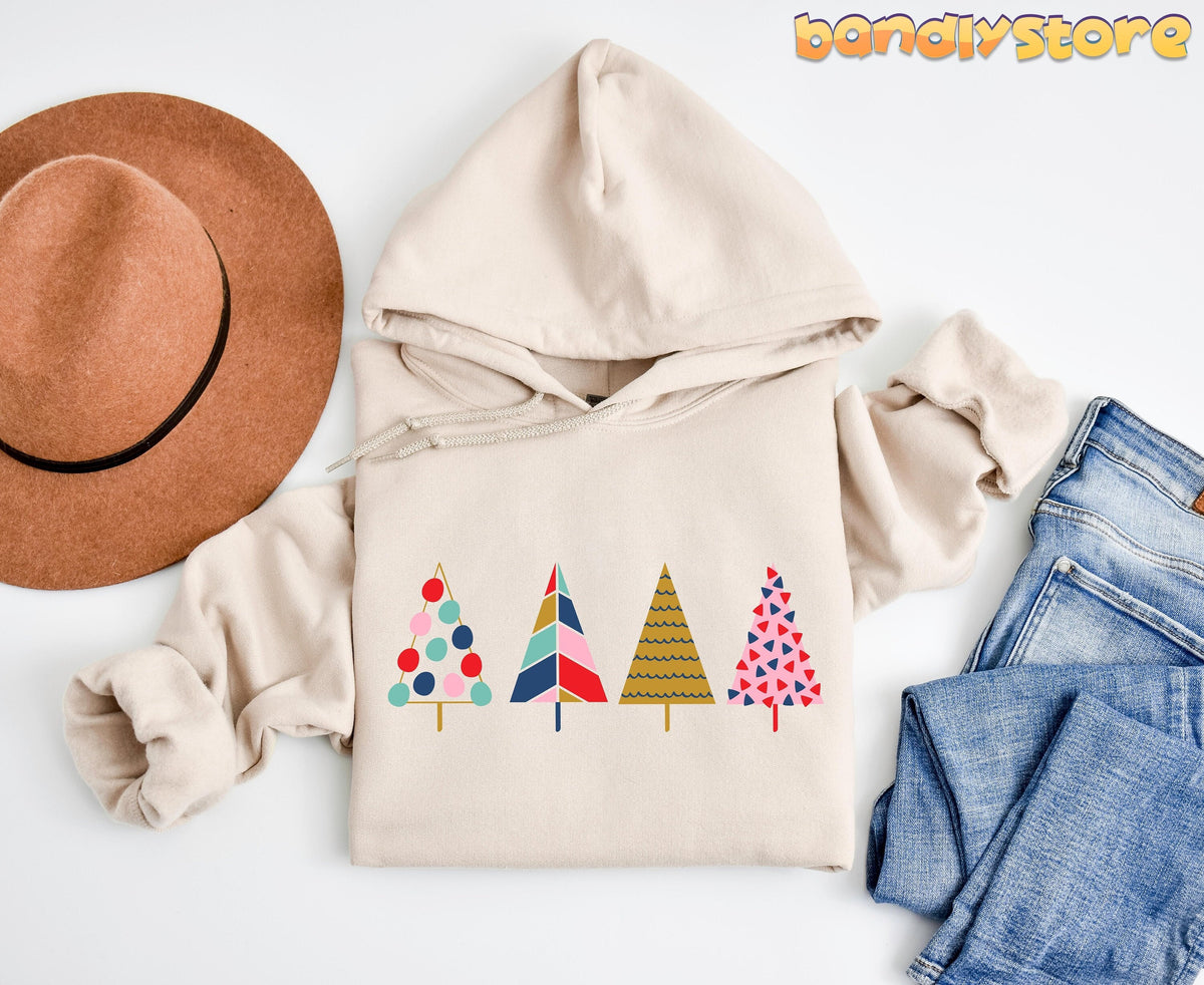 Cute Pine Trees Hoodie in sand flat-laid from above beside a brown hat and blue jeans.