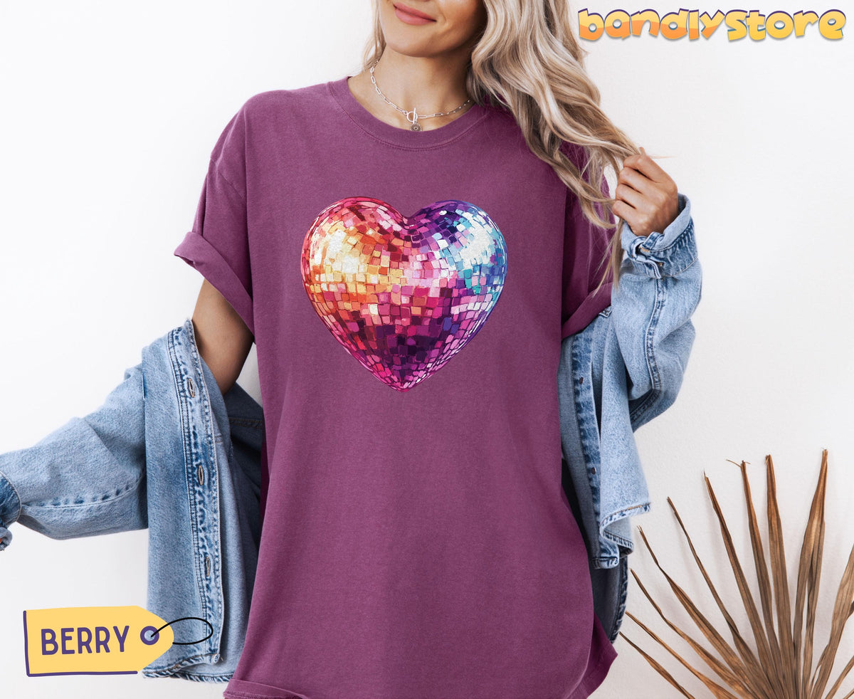 Disco Ball Heart T-Shirt in Berry on model holding denim jacket against white wall with dried leaves.