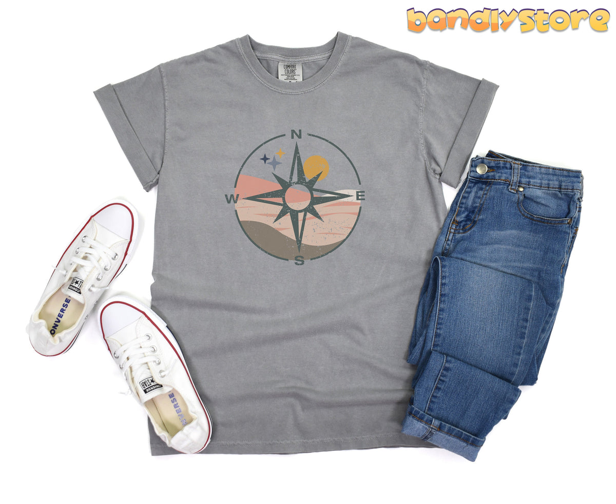 Distressed Compass T-Shirt in grey flat-laid from above beside white sneakers and blue jeans.
