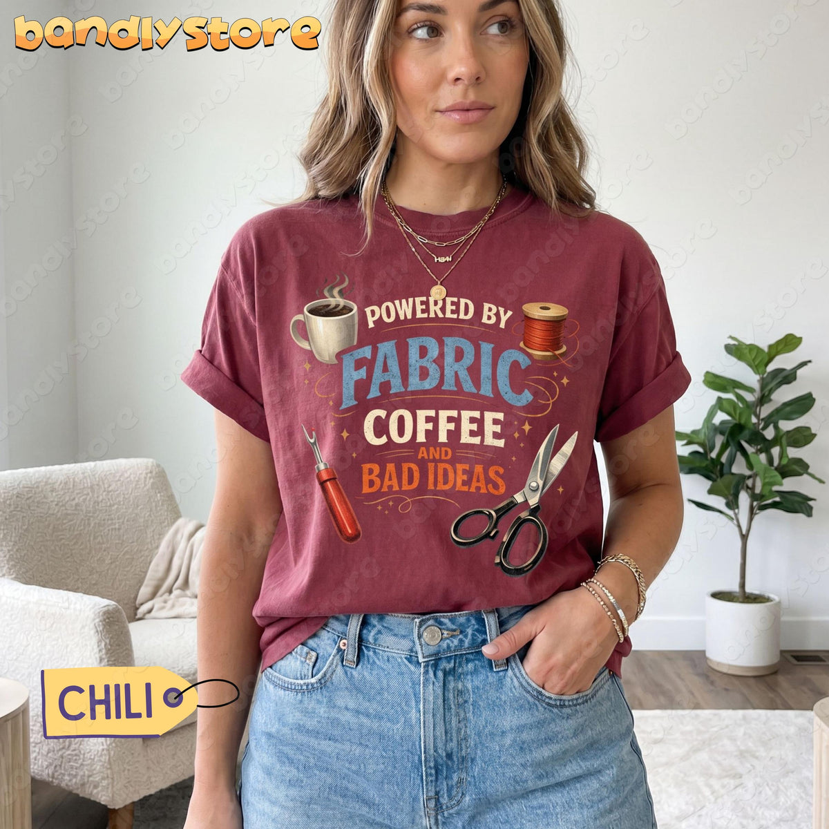 Powered By Fabric, Coffee And Bad Ideas T-Shirt in Chili on a woman standing indoors beside a plant and chair.