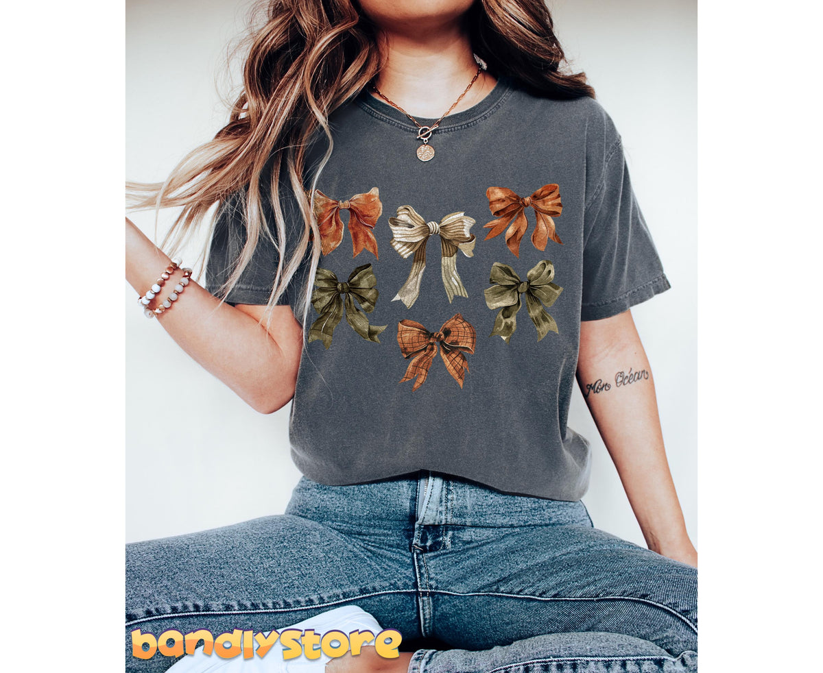 Fall Coquette Bow T-Shirt in Pepper, front view on seated model with jeans, jewelry and plain white backdrop.
