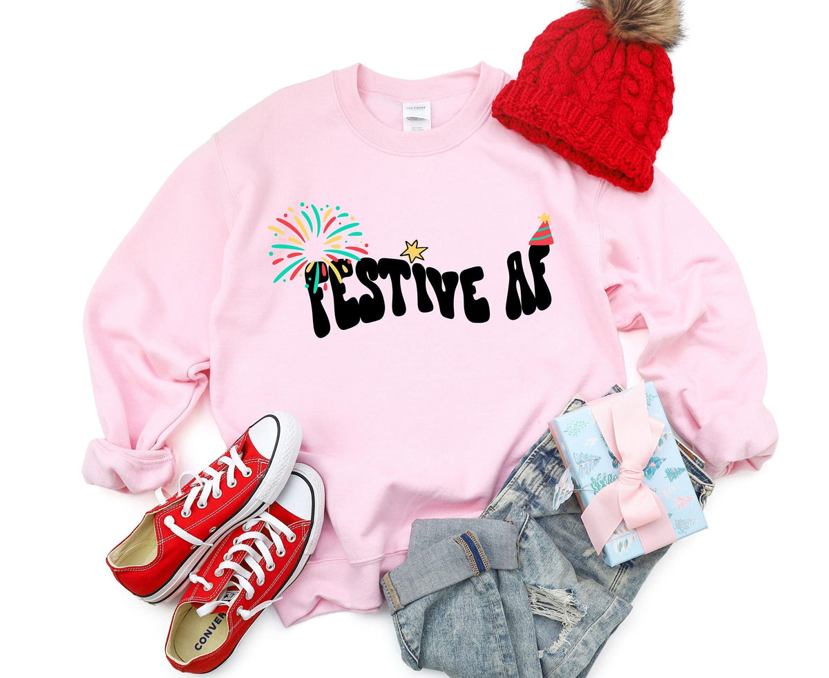 Festive AF Sweatshirt in light pink laid flat with red beanie, sneakers, jeans and gift.