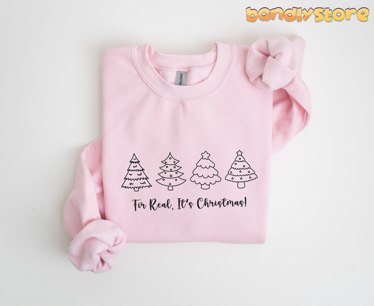 Fir Real It's Christmas Sweatshirt in light pink folded flat on a plain white surface.