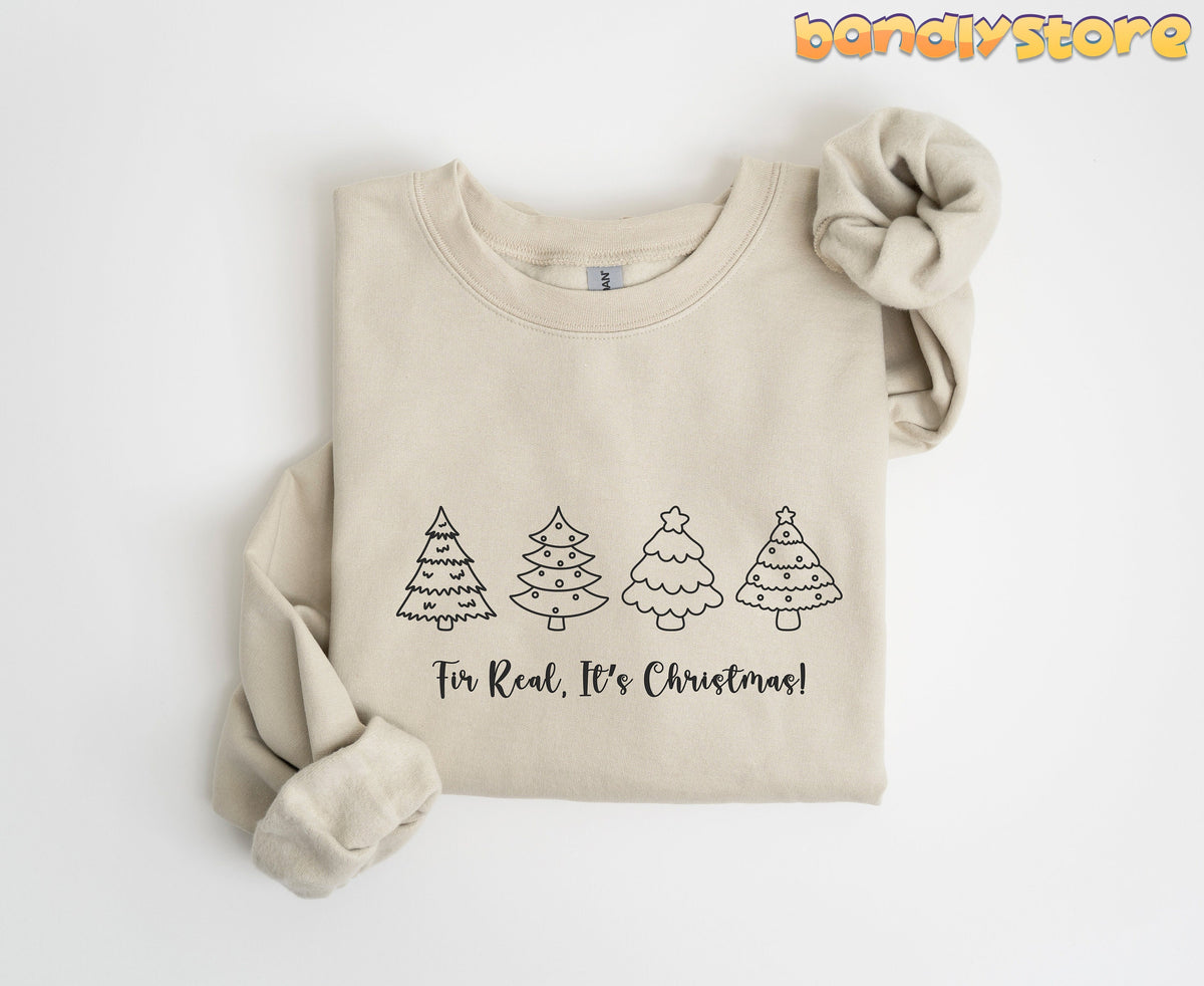 Fir Real It's Christmas Sweatshirt in sand, folded flat on white with four outline trees and sleeve rolled.