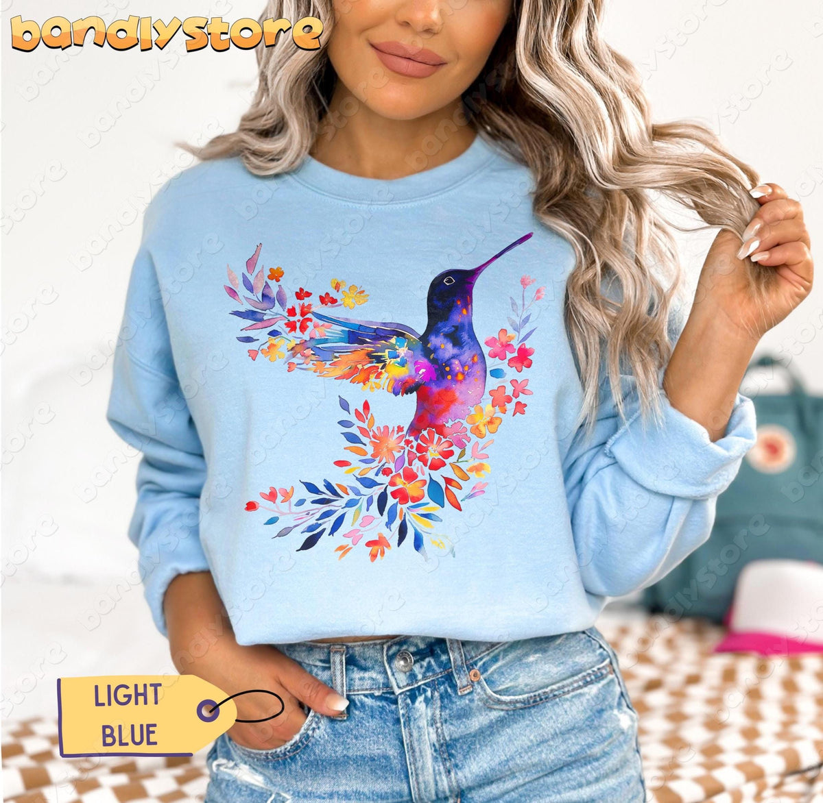 Floral Hummingbird Sweatshirt on a model in light blue, cropped front view with jeans and a bag behind.