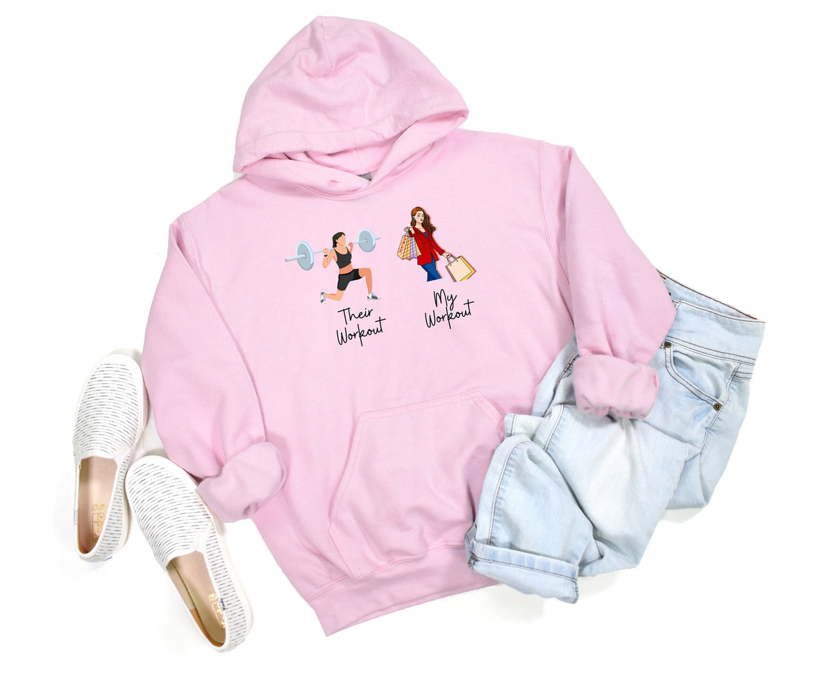 Funny Fitness Hoodie in light pink, flat-lay with white slip-ons left and rolled light-wash jeans right, gym vs shopping graphics on chest.