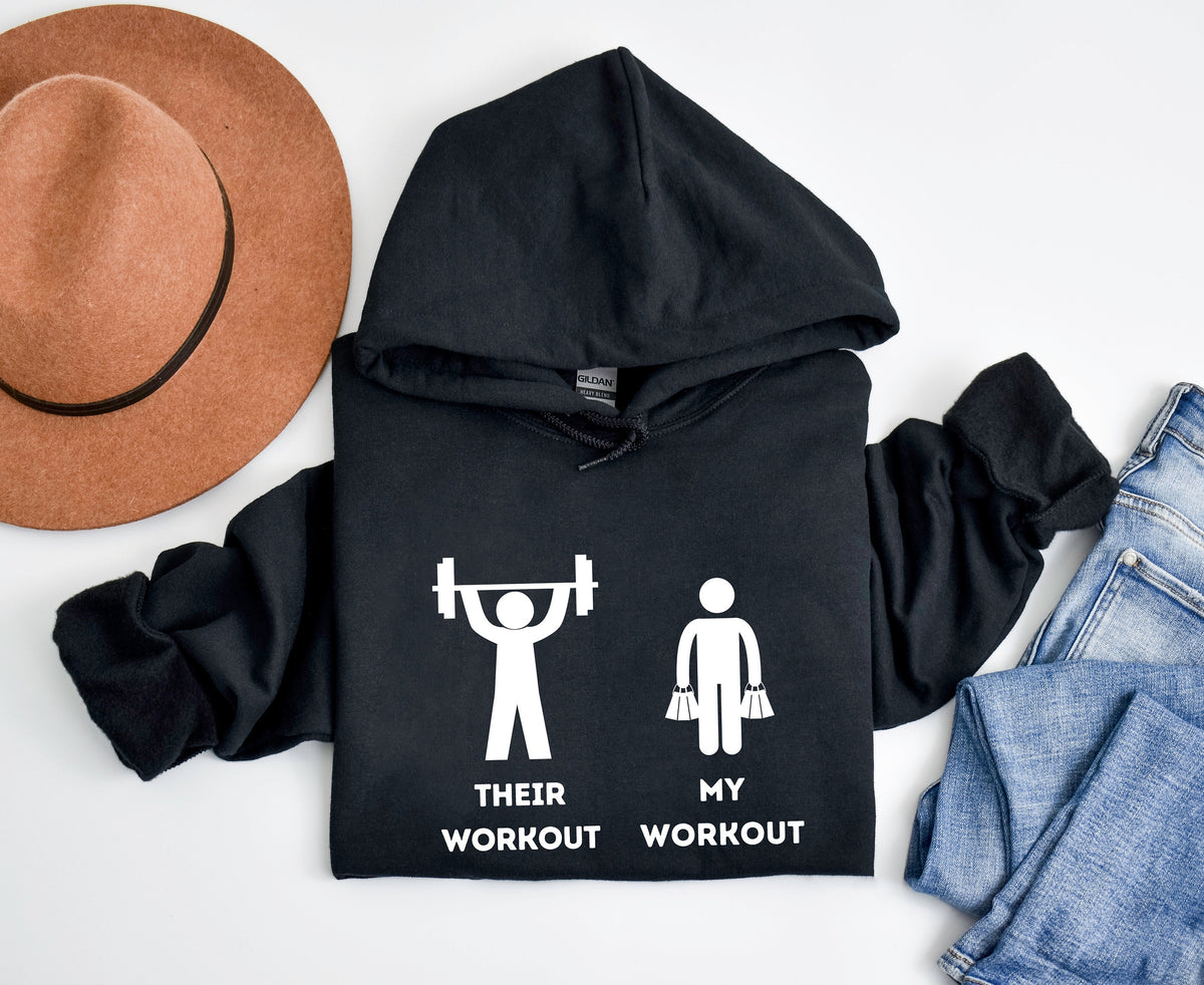 Funny Workout Hoodie in black, top-down flat lay beside a brown hat and blue jeans.