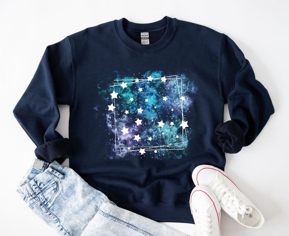 Galaxy Sweatshirt in navy laid flat on white beside jeans and white sneakers.