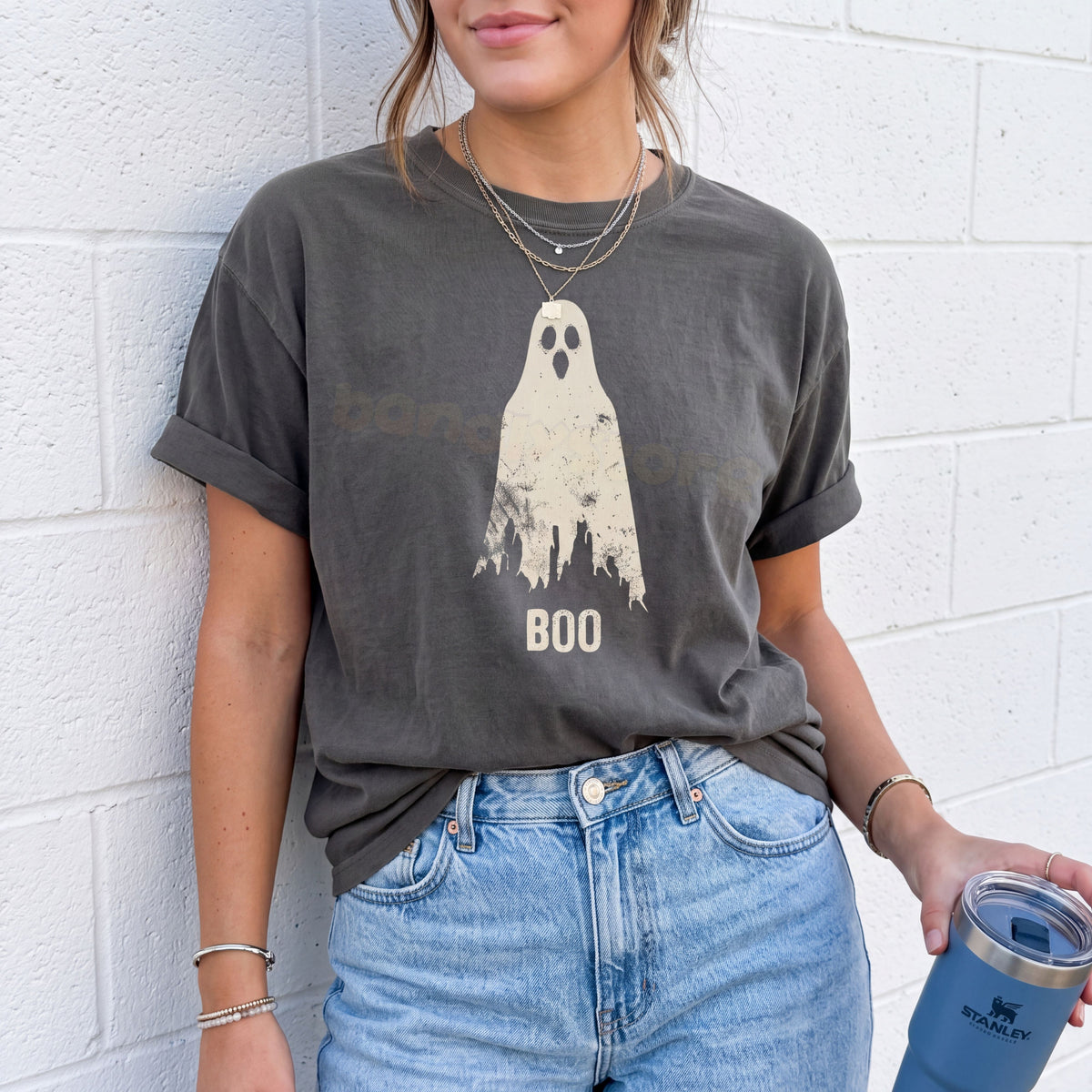 Grungy Ghost T-Shirt in Pepper on a person against a white brick wall holding a tumbler.
